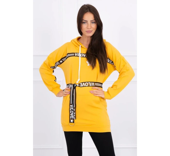 Šaty zdobené stuhou a nápisy v hořčicové barvě