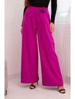 Dámske elegantné nohavice so širokými nohavicami a ozdobným kvetom tmavo fialovej farby Dámske elegantné nohavice so širokými nohavicami a ozdobným kvetom tmavo fialovej farby