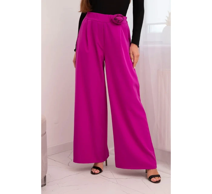 Dámske elegantné nohavice so širokými nohavicami a ozdobným kvetom tmavo fialovej farby Dámske elegantné nohavice so širokými nohavicami a ozdobným kvetom tmavo fialovej farby