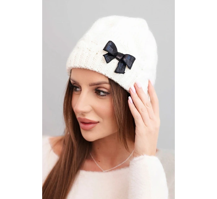 Dámska zimná čiapka s ozdobnou mašľou a vrkočovým vzorom K438 ecru Dámska zimná čiapka s ozdobnou mašľou a vrkočovým vzorom K438 ecru