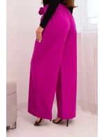 Dámske elegantné nohavice so širokými nohavicami a ozdobným kvetom tmavo fialovej farby Dámske elegantné nohavice so širokými nohavicami a ozdobným kvetom tmavo fialovej farby