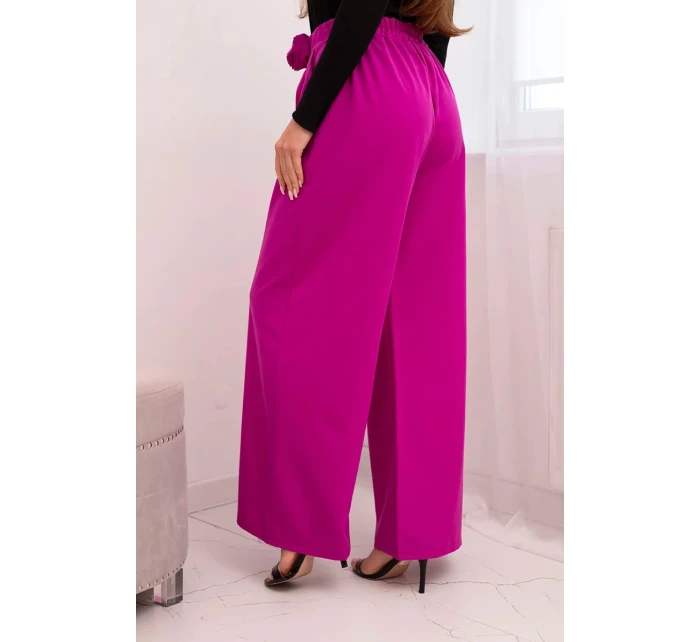 Dámske elegantné nohavice so širokými nohavicami a ozdobným kvetom tmavo fialovej farby Dámske elegantné nohavice so širokými nohavicami a ozdobným kvetom tmavo fialovej farby