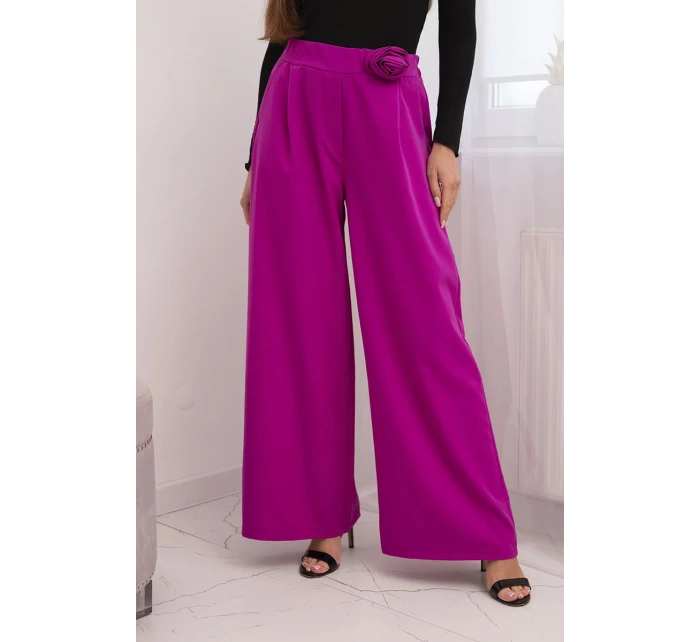 Dámske elegantné nohavice so širokými nohavicami a ozdobným kvetom tmavo fialovej farby Dámske elegantné nohavice so širokými nohavicami a ozdobným kvetom tmavo fialovej farby