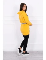 Šaty zdobené stuhou a nápisy v hořčicové barvě