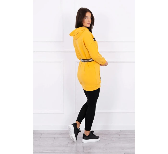 Šaty zdobené stuhou a nápisy v hořčicové barvě