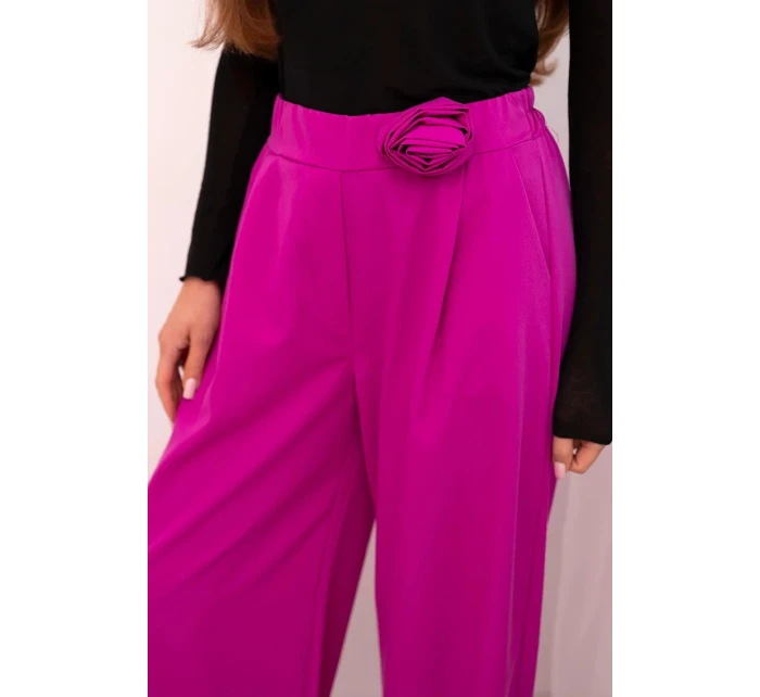 Dámske elegantné nohavice so širokými nohavicami a ozdobným kvetom tmavo fialovej farby Dámske elegantné nohavice so širokými nohavicami a ozdobným kvetom tmavo fialovej farby
