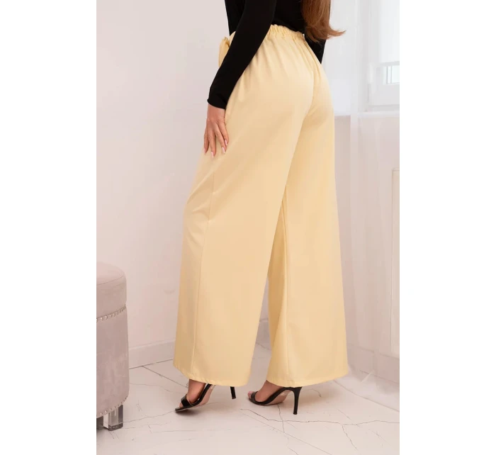 Dámske elegantné nohavice so širokými nohavicami a ozdobným kvetom žltej farby